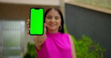 Genç kız gülümsüyor ve elinde yeşil ekranlı akıllı telefon ve kameraya yakın krom anahtar var. Dijital reklam için kişiselleştirilebilir ekranı vurguluyor.