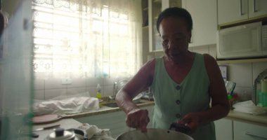 Afro-Amerikalı yaşlı bir kadın tencerede pirinç karıştırıyor. Yetenek, gelenek ve özel bir mutfak ortamında ev yapımı yemek hazırlama aşkı sergiliyor.