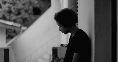 Kafası keder ve umutsuzlukla eğilmiş, çocukluk yalnızlığı ve duygusal hassasiyetini temsil eden bir duvar başında tek başına duran Afrikalı Amerikalı çocuk.