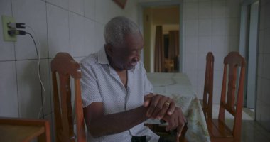 Bastonuyla mutfakta yürüyen, neşeyle gülümseyen, dengeyi, gücü ve mutluluğu sakin bir anda gösteren yaşlı Afrikalı Amerikalı adam.