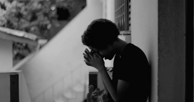 Kafası keder ve umutsuzlukla eğilmiş, çocukluk yalnızlığı ve duygusal hassasiyetini temsil eden bir duvar başında tek başına duran Afrikalı Amerikalı çocuk.