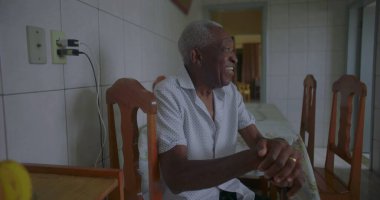 Bastonuyla mutfakta yürüyen, neşeyle gülümseyen, dengeyi, gücü ve mutluluğu sakin bir anda gösteren yaşlı Afrikalı Amerikalı adam.