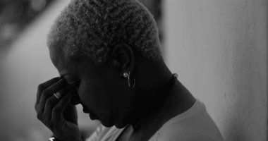 Afrika kökenli Amerikalı bir kadının derin duygusal karmaşa içinde yüzünü tek eliyle kapatması, üzüntü, pişmanlık, depresyon ve hassasiyet duygularını ifade etmesi, siyah beyaz