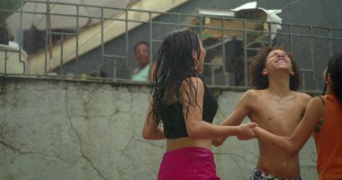 Suyun altında el ele tutuşan, gülen ve kaygısızca dönen, ferahlatıcı bir açık hava aktivitesi sırasında yaz eğlencesi yapan bir grup neşeli çocuk.