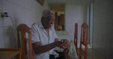 Bastonuyla mutfakta yürüyen, neşeyle gülümseyen, dengeyi, gücü ve mutluluğu sakin bir anda gösteren yaşlı Afrikalı Amerikalı adam.