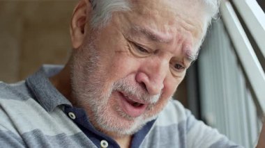 Gri sakallı ve acı çeken yaşlı adamın yakın çekimi demir garaj parmaklıklarına doğru eğiliyor dramatik ışık, duygusal gözler ve Huf ifadesi ile.