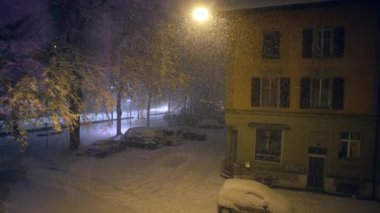 Gece eski binanın yakınına kar yağıyor. Sarı cephe karşısında usulca parlıyor. Nostaljik sakin kış şehri manzarası yaratıyor.