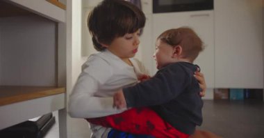 Ağabeyi mutfakta oturmuş, bebeğini kucağında tutuyor, hem sakin hem de bağlı, şefkatini, sıcaklığını ve evdeki aile sevgisinin duygusal bağını ifade ediyor.