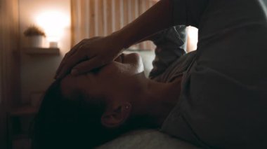 Yüzü tükenmiş bir şekilde yatakta yatan kadın, loş bir evde duygusal yorgunluk, stres ve sessiz mücadele gösteriyor.