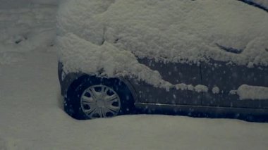 Araba kış gecesi yoğun karla kaplı soğuk kentsel ortamda yoğun kar yağışı ve durgunluğunu gösteriyor.