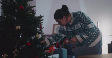 Annem Noel ağacını sessiz oturma odasında tek başına süsledi. Huzurlu bir hazırlık, yansıma ve sıcak bir kış tatili geçiriyor.