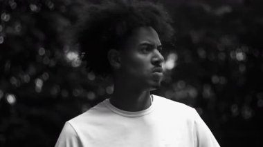 Siyah beyaz giyen Afro-Amerikan adam gergin bir ifadeyle yan yana bakıyor, kızgın ve dalgın görünüyor, hayal kırıklığını, tefekküre dalmayı ve iç gücünü yansıtıyor.