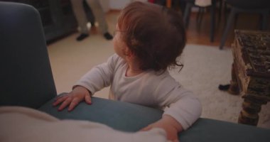 Küçük çocuk kanepeyi tutarken sevinçle gülüyor, mutluluğu, oyunculuğu ve aile bağlarını erken çocukluk evlerinde yakalıyor..