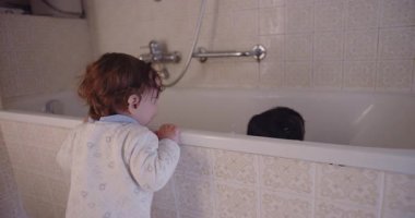 Küçük çocuk küvetin yanında durmuş ağabeyinin aile banyosunda banyo yapmasını izliyor. Kardeş bağı merakını ve evde günlük aile yaşantısını anlatıyor..