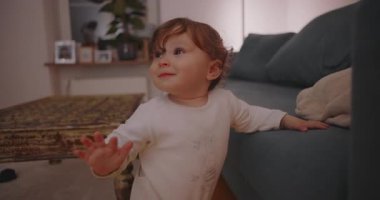 Yürüyen çocuk, aile ortamında çocukluk dengesi, büyüme ve keşfi gösteren tuhaf ifadelerle destek için koltuğunu tutarken,.