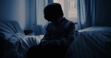 Kafası eğik, loş mavi ışıklı bir odada yatağın kenarında oturan çocuk çocukluk yalnızlığını, melankoliyi ve sessiz duygusal mücadeleyi aktarıyor.