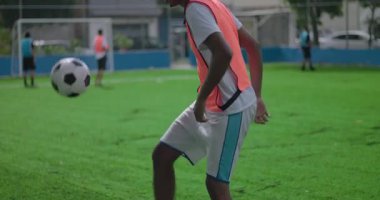 Brezilya asıllı, Afrika kökenli, yeşil sahada futbol topuyla hokkabazlık yapan, açık havada tek başına antrenman yaparken denge, çeviklik ve güven sergileyen Brezilyalı adama yaklaş.