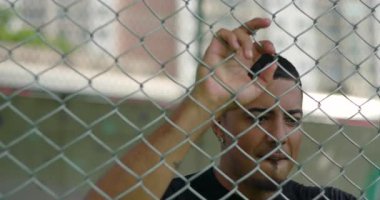 Öfke ve hüsran içinde metal çitleri kavrayan Latin kökenli Latin kökenli bir adam. Duygularıyla vuruyor. İç savaş sırasında derin pişmanlık, umutsuzluk ve başkaldırı gösteriyor.