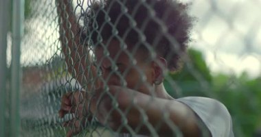 Genç Afrikalı Amerikalı adam derin düşüncelere dalmış, dışarıda duygusal mücadele ve izolasyon gösteriyor.