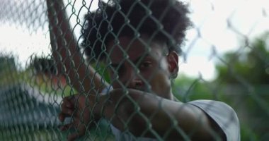 Afrika kökenli Latin kökenli bir adam yoğun bir bakışla başını kameraya çevirir. Duygusal gerilim ve iç çatışma anında çitin üzerinde dinlenen bir kol.