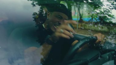 Direksiyon başında oturan bir adam, park halindeki arabada stres, hayal kırıklığı ve duygusal yorgunluk belirtileri gösteriyor.