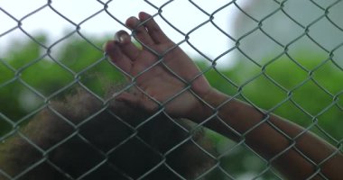 Genç Afrikalı Amerikalı bir adam gerginlik ve içgözlem anında çitlere yaslanıyor. Duygusal mücadele ve iç çatışma gösteriyor.