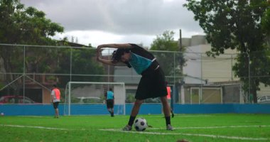 İspanyol adam maçtan önce futbol sahasında ısınıyor ve ısınıyor, vücut ve zihni açık hava parkında odaklanma ve koordinasyona hazırlamak için spor hareketleri yapıyor.