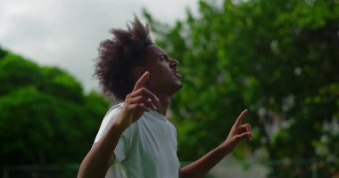 Afrika kökenli genç adam elini kaldırıyor ve yukarı bakıyor, neşe, inanç ve umut ifade ediyor, ruhsal uyanışı ve açık havada yüksek güçle olan bağlantısını kutluyor.