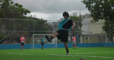İspanyol adam yeşil alanda futbol tekmeleri atıyor koordinasyon ve çeviklik gösteriyor, şehir ortamında rahat antrenman sırasında top kontrolü uyguluyor.