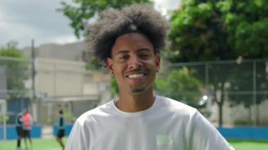 Genç Afrikalı Amerikalı bir adam antrenmandan sonra futbol topunu tutuyor. Takım çalışmasını, motivasyonu ve sporun neşesini sembolize ediyor.