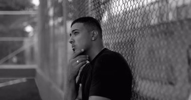 Latin kökenli, Afrika kökenli, tel örgülere yaslanmış, düşüncelere dalmış, düşüncelere dalmış, umut dolu, ve sinematik siyah beyaz portrede sessiz bir gücü olan bir Latin.