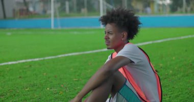 Afrika kökenli Latin kökenli genç bir adam futbol sahasında tek başına oturuyor. Yoğun bir maçtan sonra topu tutuyor, düşüncelere dalmış ve duygusal bir yansımayla başka yere bakıyor.