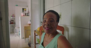 Sıcak bir mutfak ortamında yemek masasında sıcak bir şekilde gülümseyen, sıcaklığı, mutluluğu ve hoş bir atmosferi olan yaşlı Afrikalı Amerikalı kadın.