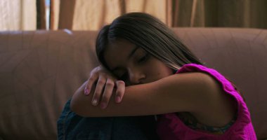 Genç kızın başını kollarının üzerinde dinlendirme, üzüntü, yalnızlık ve içgözlem, çocukluk depresyonu ve duygusal izolasyon temalarını vurgulama.