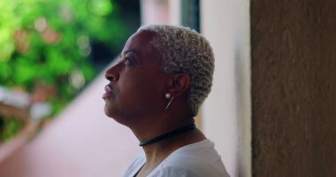 Derin düşüncelere sahip bir kadın, kapalı gözlerle duvara karşı duruyor, duygusal ifade, açık hava düzeni, yakın plan, Afrika kökenli, pişmanlık, sıkıntı, duygusal karmaşa