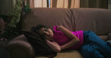 Uzak bir bakışla kanepede uzanan genç kız, sakin, ev ortamında yalnızlık, üzüntü ve çocukluk duygularını ifade ediyor.