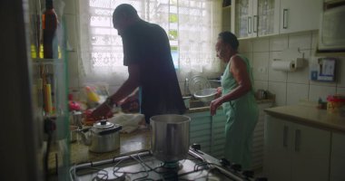 Afrikalı bir kadın mutfakta yemek pişiriyor, sobanın yanında yemek hazırlıyor, buhar yükseliyor, günlük hayatı, yemek hazırlıklarını ve aile anlarını gözler önüne seriyor.