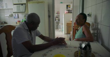 Afrika kökenli yaşlı bir çift yemek masasında düşünceli bir anı paylaşıyor, aile bağları, aile bağları, ve bir ev ortamında günlük yaşamın basitliği.