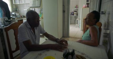 Afrika kökenli yaşlı bir çift yemek masasında düşünceli bir anı paylaşıyor, aile bağları, aile bağları, ve bir ev ortamında günlük yaşamın basitliği.