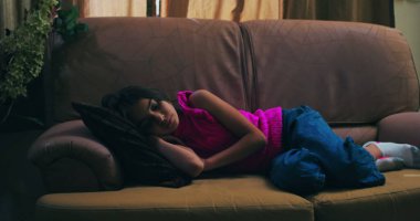 Kanepede uzanmış, kafası yastıkta dinleniyor, gözleri kapalı, yalnızlık, üzüntü, çocukluk bunalımı, ve sessiz bir ev ortamında duygusal hassasiyet temaları somutlaştırıyor.