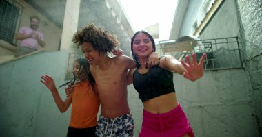 Çocuklar arka bahçede toplanırken suda gülüp oynuyorlar, el ele tutuşuyorlar ve açık havada kaygısız ve neşeli bir anın tadını çıkarıyorlar.