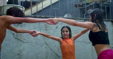 Gençler yağmurda dönüyorlar, el ele tutuşuyorlar ve gülüyorlar, beraberlik, çeşitlilik ve neşe sergiliyorlar.