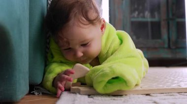 Bebek yerde yatar, paspas dokusunu inceler, erken gelişim sırasında dokunsal keşif ve duyusal öğrenme odaklı ve sakin anı