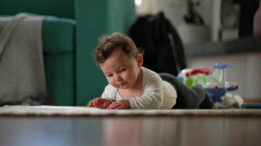 Bebek karnını doyururken kollarını kaldırıyor, erken gelişimin neşeli ve kararlı anı, güvenli ev ortamında güç, merak ve keşif gösteriyor.