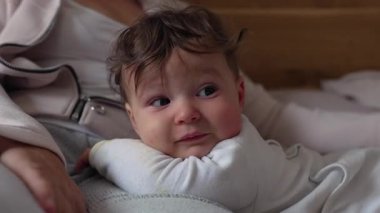 Bebeğin gülümsemesi, ebeveyne yakın yatarken sıcak ve sevgi dolu bir an. Aile evinde bağları, güvenliği ve erken duygusal bağları ifade ediyor.