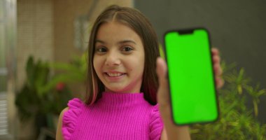 Elinde yeşil ekran ve krom anahtarı olan akıllı telefonu tutan genç bir kız. Kameraya yakın gülümsüyor ve dış mekanda kişiselleştirilebilir görüntüler sergiliyor.