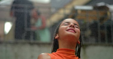 Serin sudan hoşlanan bir kız, gözleri sükunetle kapalı, kaygısız neşe ve sükuneti ifade eden, sıcak bir açık havada ferahlatıcı bir anın tadını çıkaran bir kız.