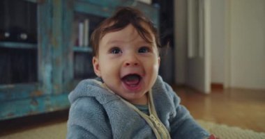 Bebek evde neşeyle gülüyor, açık ağızlı ve parlak gözlü mutlu bebeğe kapanıyor, saf heyecan, merak ve duygusal bağ kuruyor.