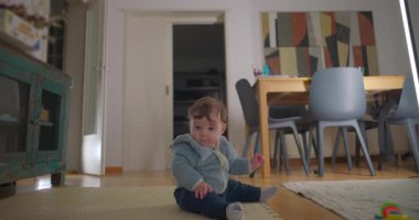 Bebek mindere hafifçe yaslanmış ev içi rahatlığında odaklanmış ifade, denge konsepti, vücut farkındalığı ve erken motor gelişimi ile birlikte.