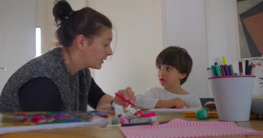 Anne, küçük oğluna ev ödevlerinde yardım ediyor, öğrenim etkinliği, eğitim konsepti, aile desteği, sabır ve çocukluk gelişiminde çocuğa rehberlik ediyor.